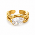A gold-plated open shank ring featuring a large, bezel-set pear-cut clear gemstone, shown on a clean white background.