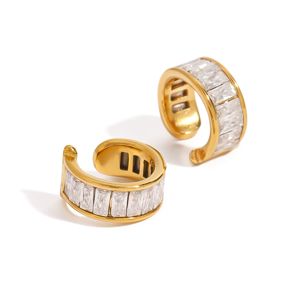 Gold cuff earrings with clear gemstones on a white background