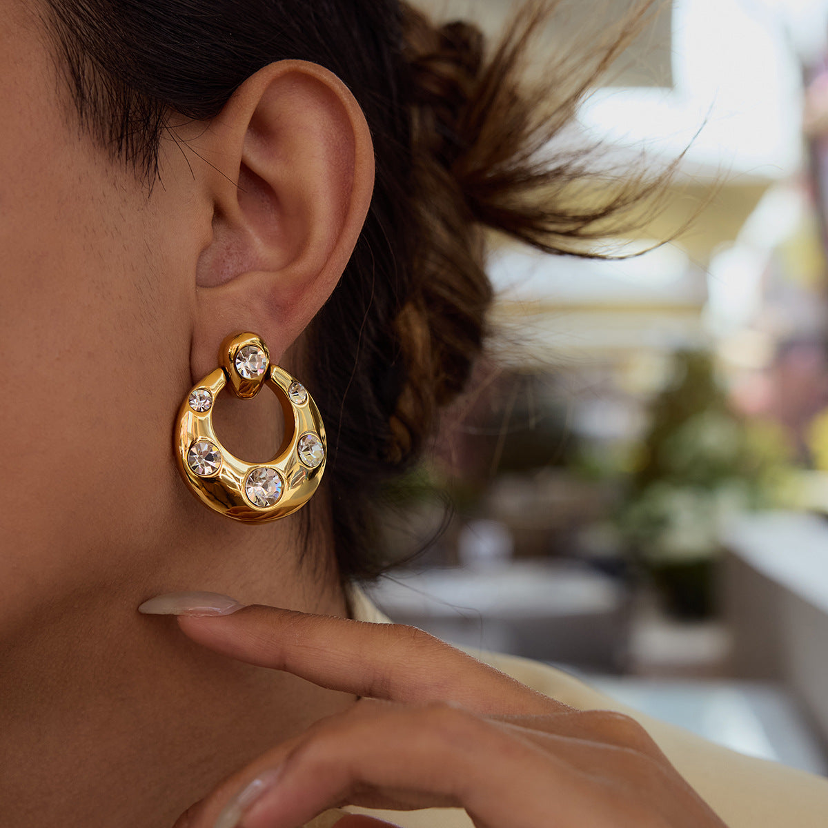 Chunky gold open circle earrings with scattered bezel-set cubic zirconia stones and CZ stud top on white background