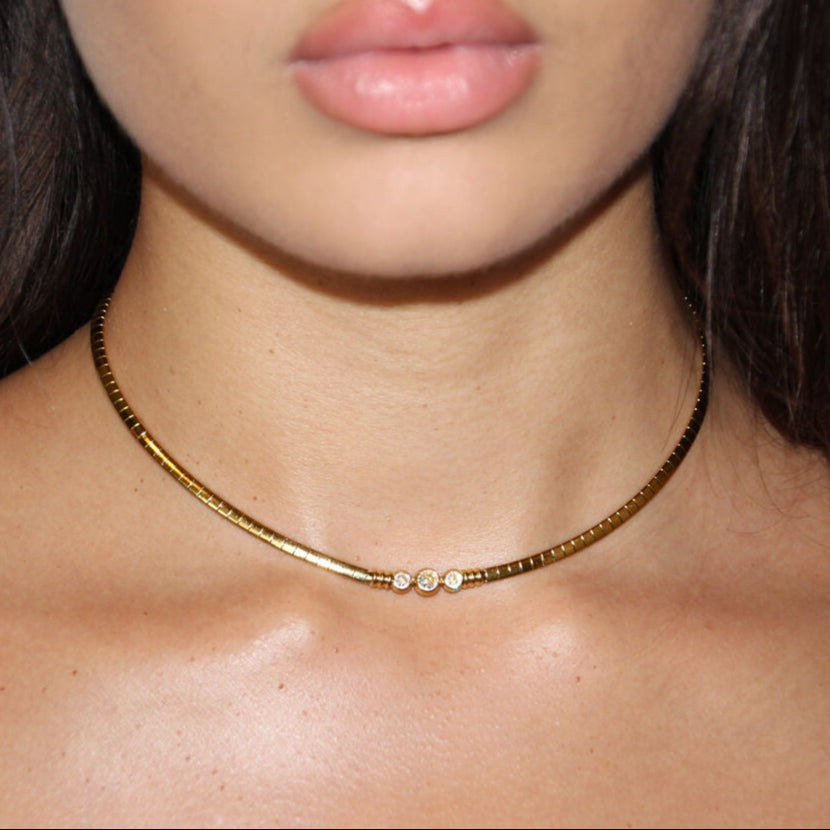 Gold choker necklace with a twisted chain and three small sparkling stones