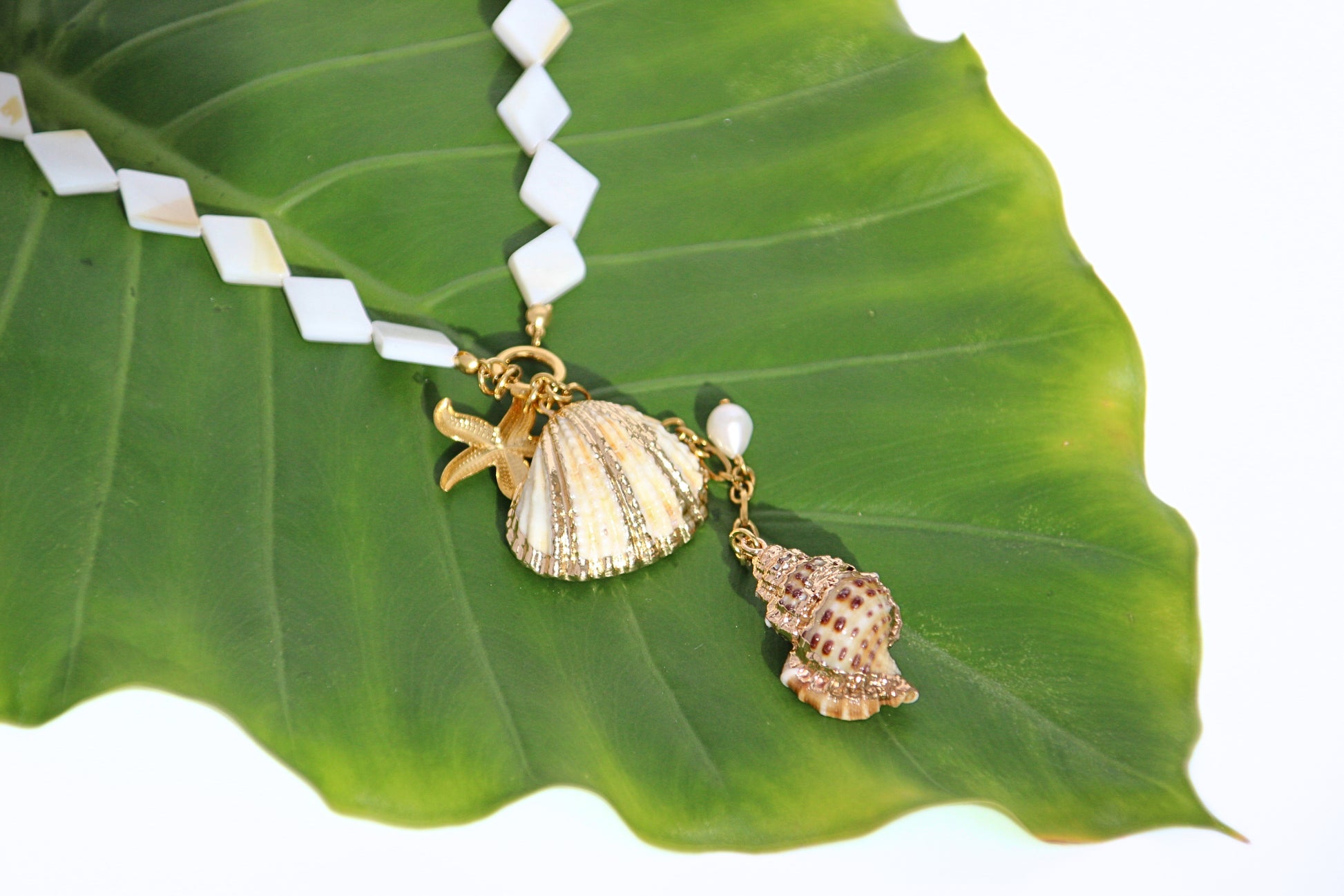 Gold-tone necklace with mother-of-pearl beads, starfish, shell, conch charms, and pearl