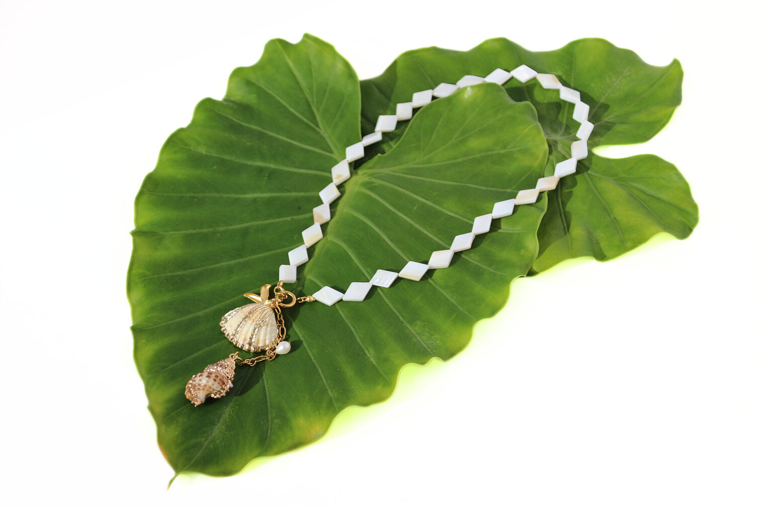 Gold-tone necklace with mother-of-pearl beads, starfish, shell, conch charms, and pearl